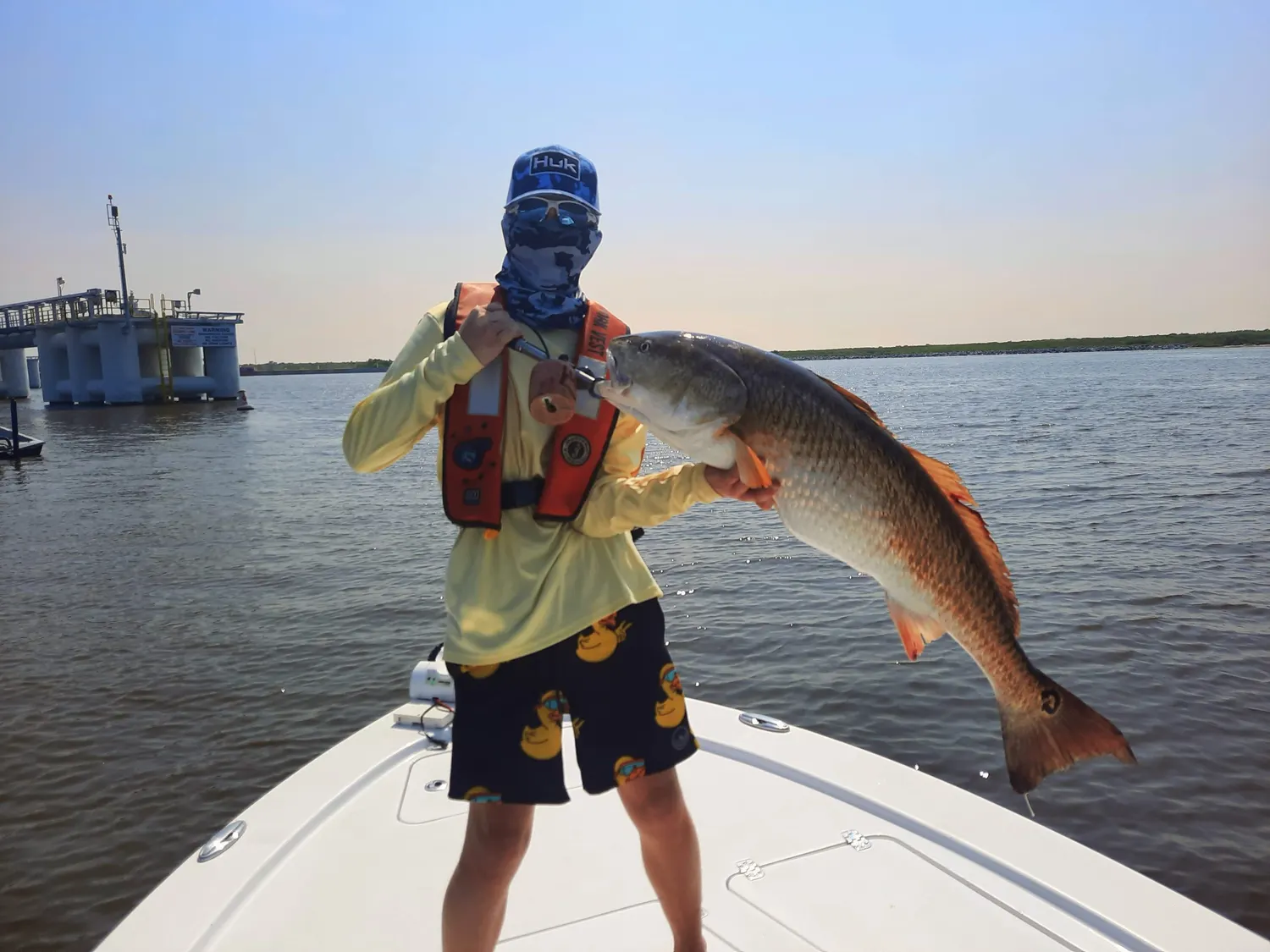 An angler holding a redfish on the bow of the boat